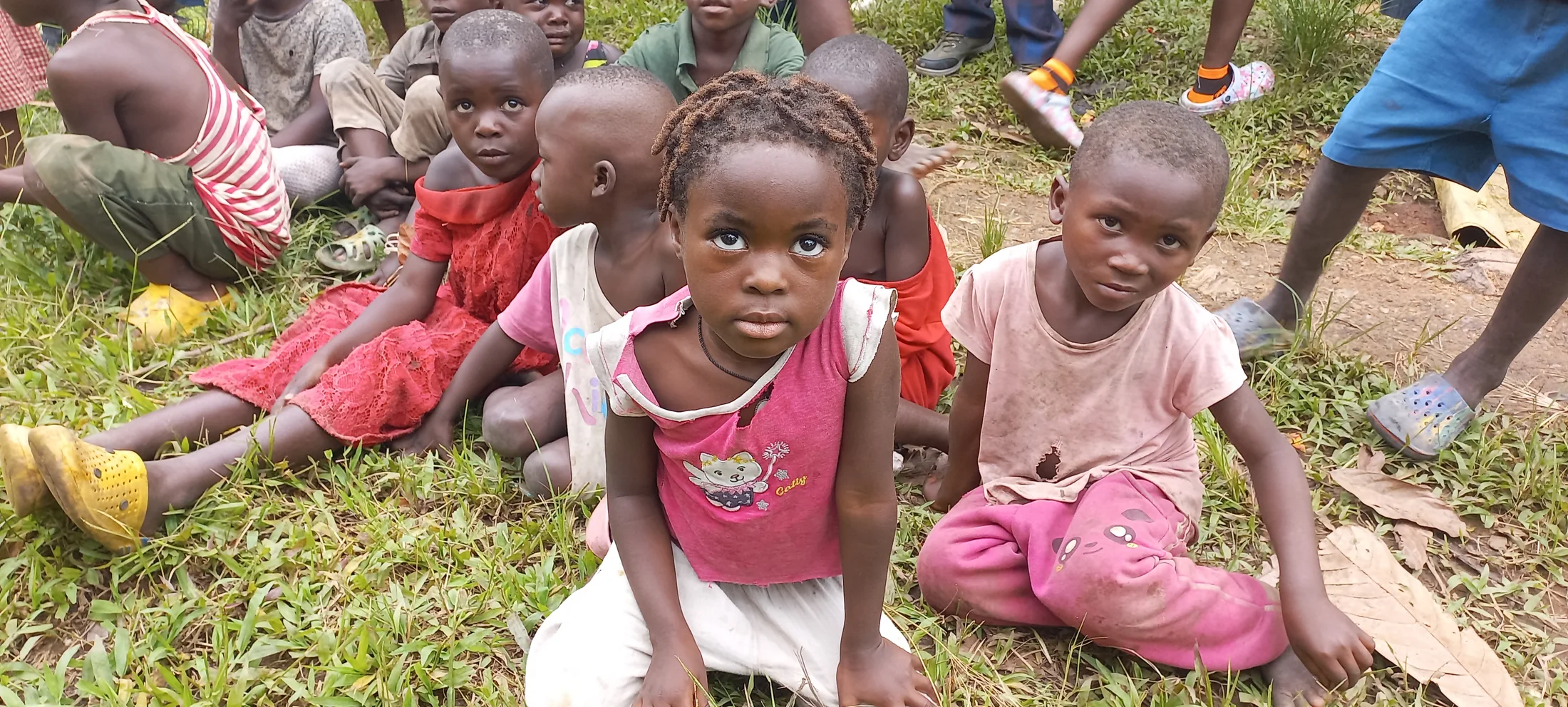 A group of children sitting and playing together outdoors.