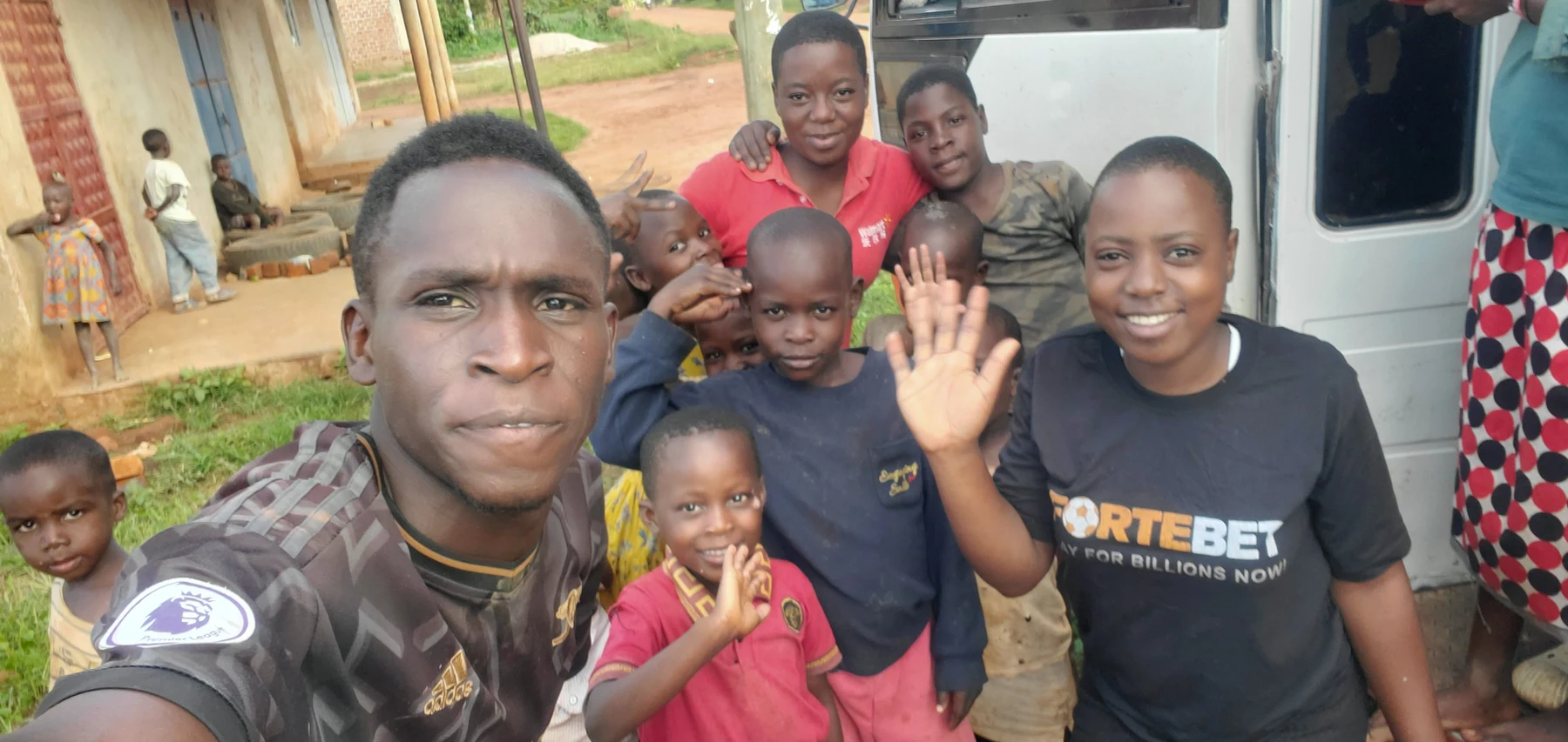 An adult and children gathered outdoors beside a white vehicle.